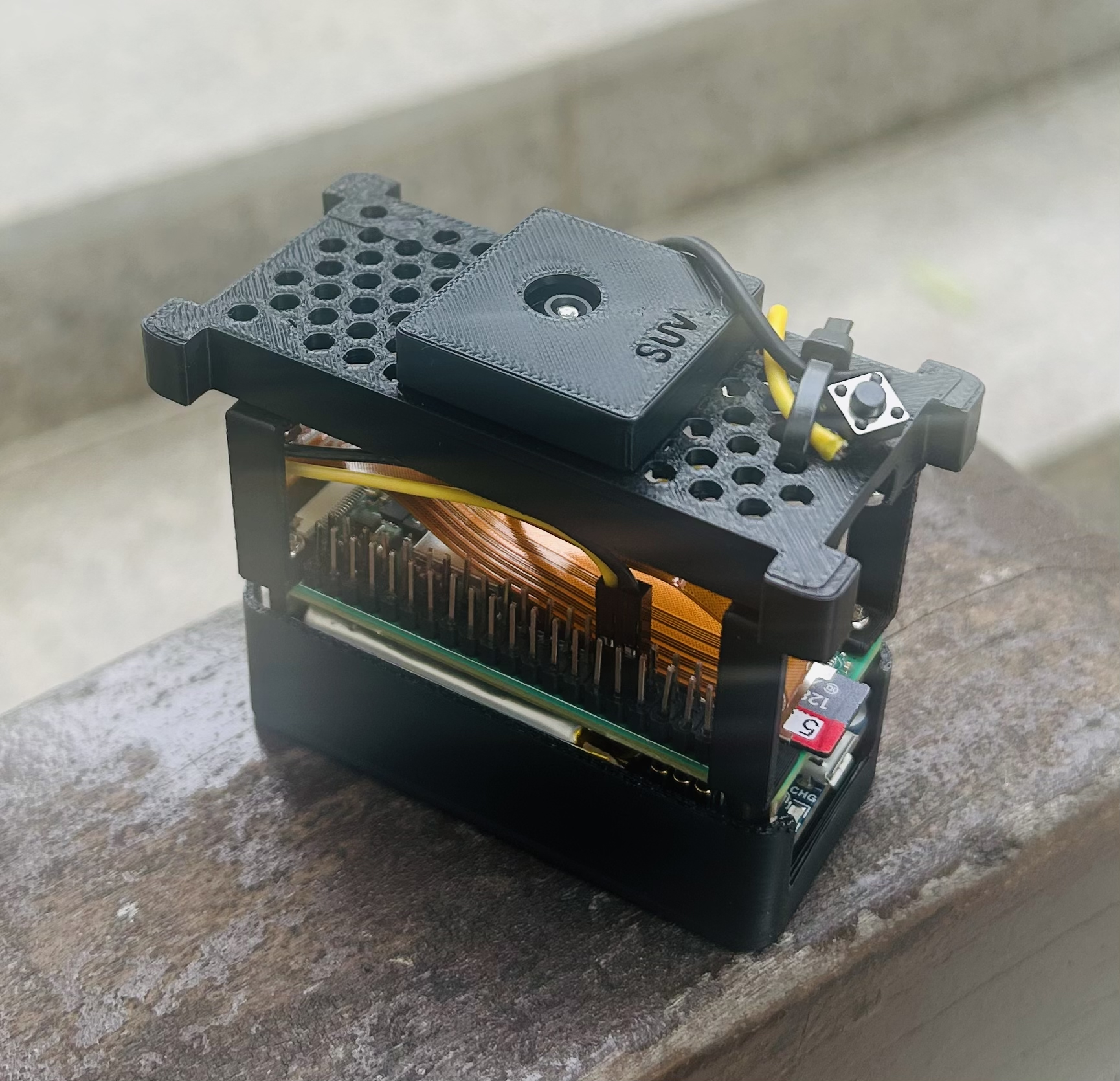 v0 camera: stacked Raspberry Pi and UPS cases with exposed wiring and a shutter button on top